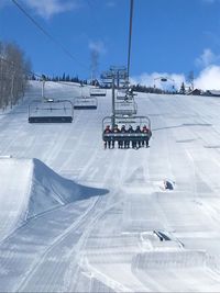 Ski lift over snow covered mountain against sky