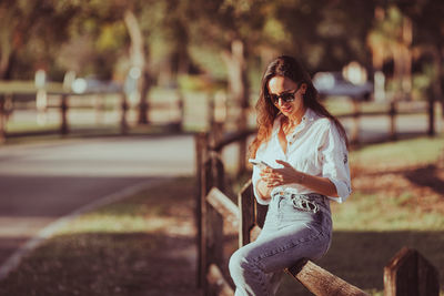 Side view of young woman sitting on railing