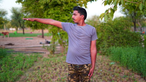 Healthy man doing stretching exercise on green grass at park. yoga day concept