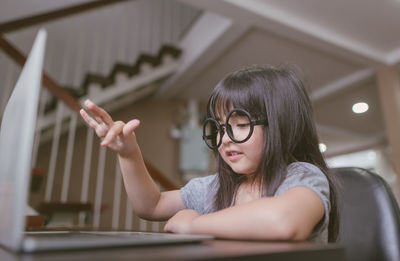 Girl wearing eyeglasses while using laptop at home