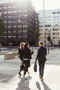 Rear view of entrepreneurs discussing business strategy while walking outdoors