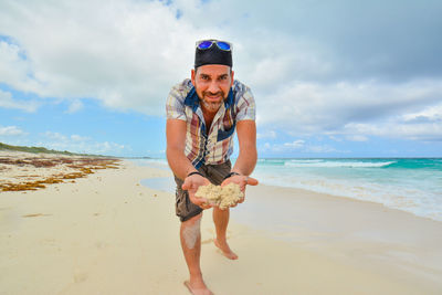 Portrait of happy boy standing on beach against sky