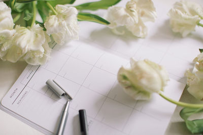 Close-up of white flowers on book at table