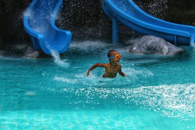 Happy boy swimming in pool at water park