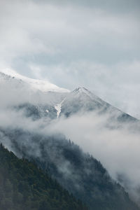 Scenic view of a mountain surrounded by clouds against sky