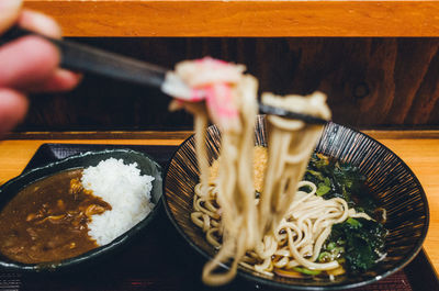 Cropped image of hand holding noodles in restaurant