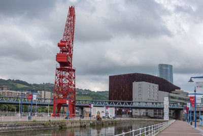 Cranes against buildings in city against sky