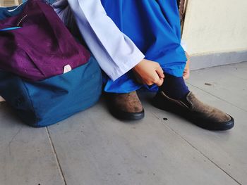 Low section of woman wearing shoe on floor