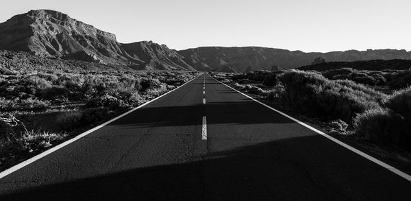 Road by mountains against clear sky