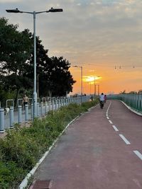 Street by road against sky during sunset