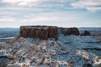 Rock formations on snow covered land against sky