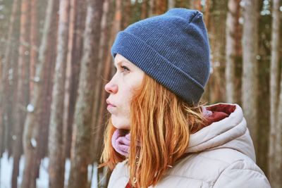 Close-up of young woman standing against trees during winter