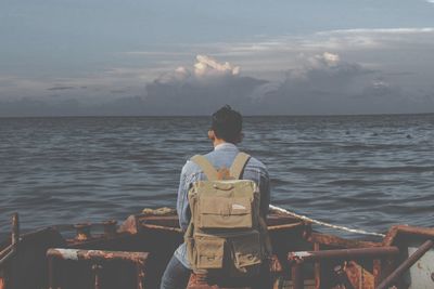 Rear view of man looking at sea against sky