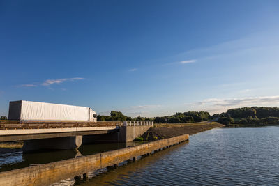 Truck on bridge over river against sky