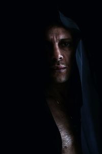 Portrait of man in hood clothing against black background