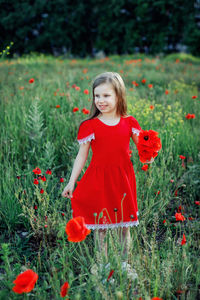 Portrait of woman with red flowers on field