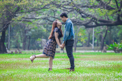 Rear view of couple on grassland against trees