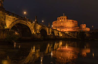 Illuminated bridge over river against sky at night