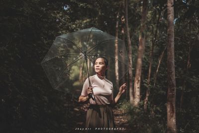 Full length of woman standing by tree during rainy season