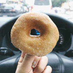 Cropped hand holding donut in car