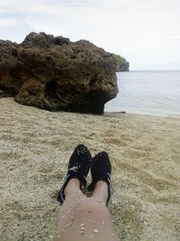 Low section of woman on beach against sky