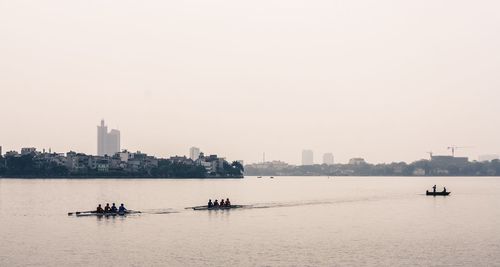 People rowing boats in west lake against clear sky