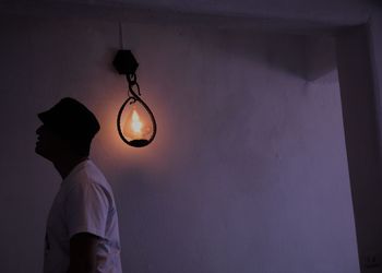 Rear view of man standing against illuminated wall