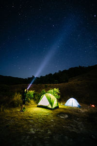 Tent on field against sky at night with photographer 