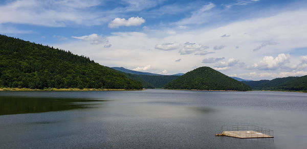 Scenic view of lake by mountains against sky