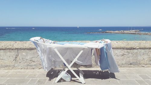 Deck chairs on beach against clear blue sky