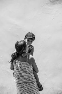 Rear view of mother and girl with arms outstretched