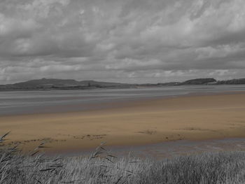 Scenic view of beach against cloudy sky