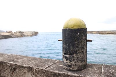 Close-up of camera against sea against clear sky