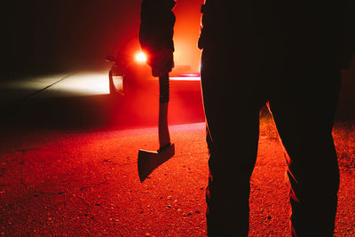 Low section of man standing on illuminated street at night