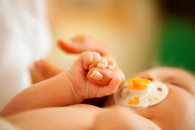 Close-up of baby holding mother finger