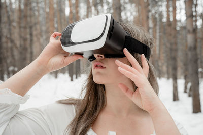 Woman wearing virtual reality simulator against trees outdoors