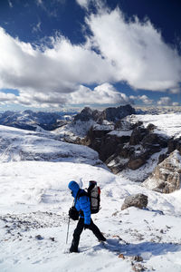 Rear view of woman standing on snowcapped mountain against sky