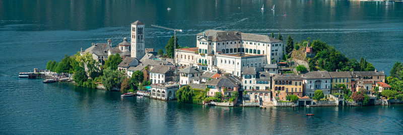 Sailboats in city by sea against buildings