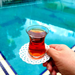 Cropped hand of woman holding drink on table