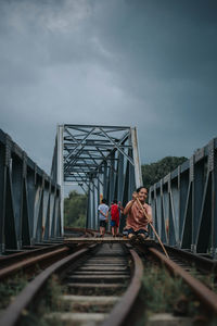 Bridge over railroad tracks against sky