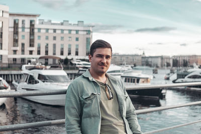 Portrait of young man standing against bridge