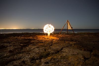 Man by burning wire wool at rocky shore