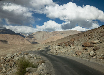Scenic view of road by mountains against sky