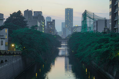 Canal amidst buildings in city against sky at dusk