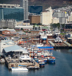 High angle view of sailboats moored on sea against buildings in city