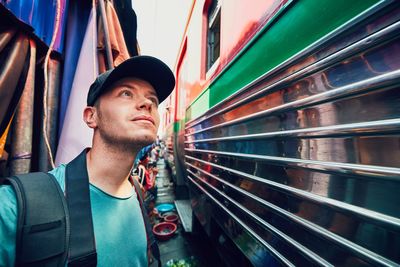 Young man standing by bus on road