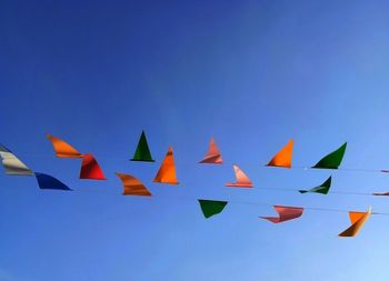 Low angle view of flags against clear blue sky