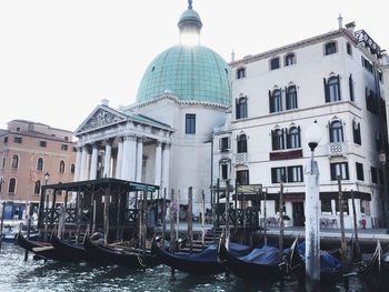 Boats moored in canal against buildings in city