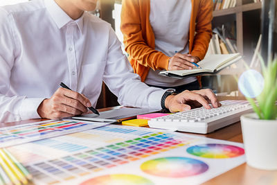 Midsection of creative business people discussing at desk in creative office