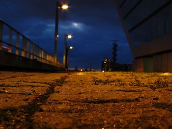 Surface level of illuminated road against sky at night